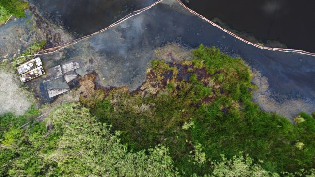 An aerial image of an oil sheen in an area with pollution boom.