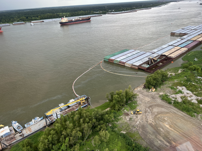 An aerial image of pollution boom around several barges.