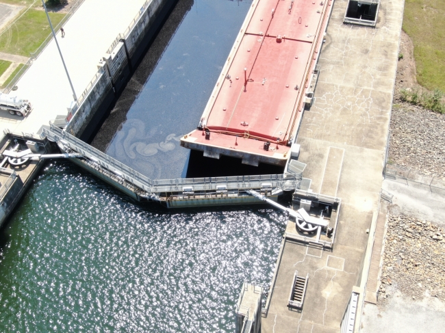An aerial photo of a barge in a river lock with a dark substance in the water in the lock. 