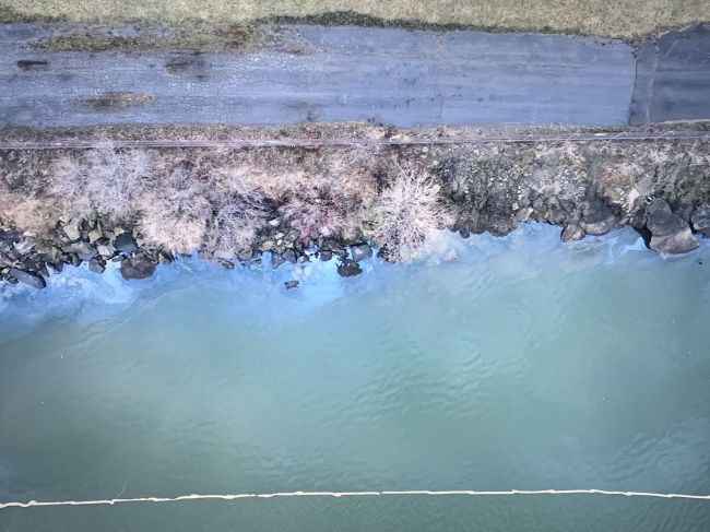 An aerial image of oil in water along a shoreline.