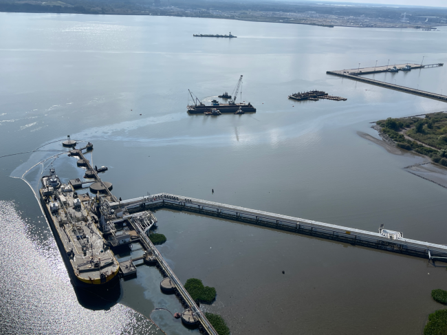 Overflight view of tank barge at terminal with oil visible in the water surrounding the barge.