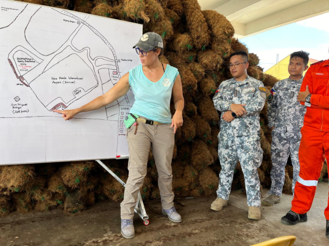 Individual points to visual diagram of shoreline oil conditions with members of Philippines Coast Guard.