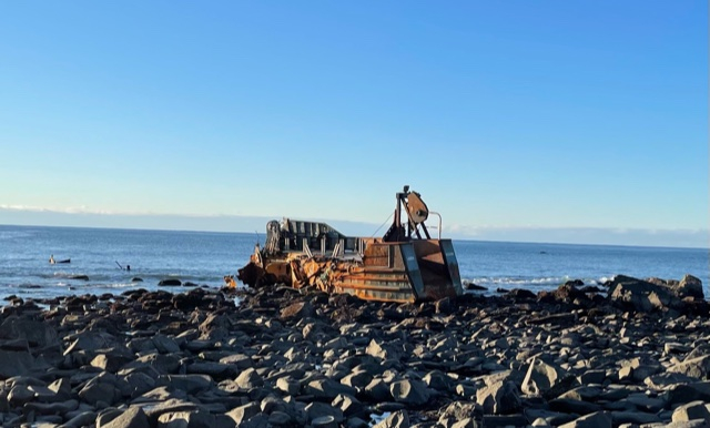 A vessel grounded on a rocky beach.