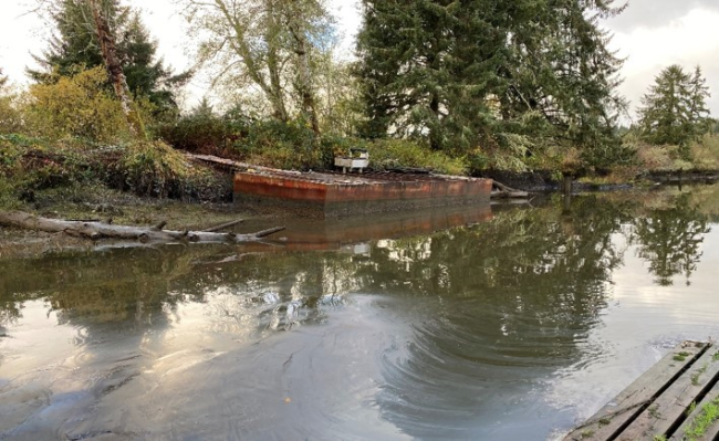 A derelict barge in a body of water.