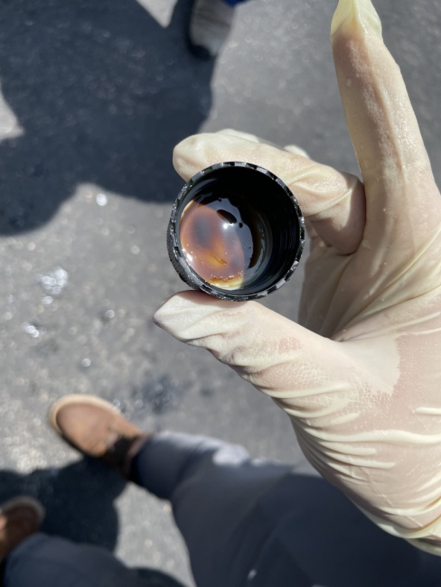 A responder holds a cap of a collected oil sample.