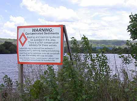 A warning sign in front of a body of water. 