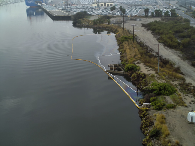 Aerial image of containment boom (yellow) and sorbent boom (white) deployed to capture oil and sheen discharging from the stormwater outfall in Dominguez Channel.