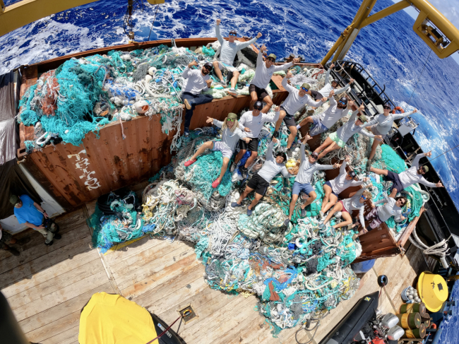 A group of people standing next to piles of marine debris.