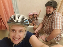 A family of four all wearing helmets with two children in a bathtub.