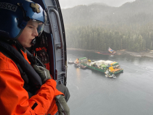 A person on a helicopter looking out at a grounded vessel.