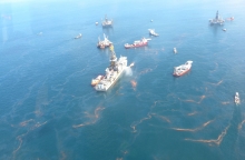 An overflight image showing a drilling rig with oil around it. 