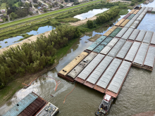 An aerial image of a group of barges with pollution boom around it.