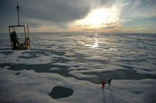 A landscape view of an ice-covered sea, with several people in the foreground. 