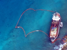 An aerial view of a grounded ship with pollution boom surrounding it. 
