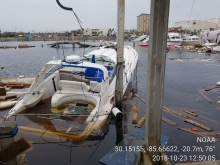 A partially submerged vessel in water surrounded by debris.
