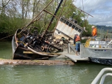 Responders next to a vessel leaning on its side.