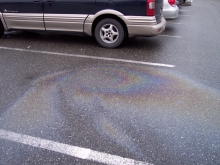 A rainbow-colored sheen on a puddle in a parking lot. 