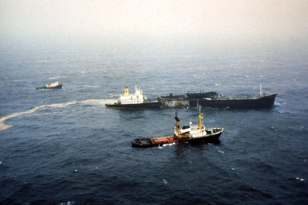 A vessel sinking in water with several other vessels surrounding it.