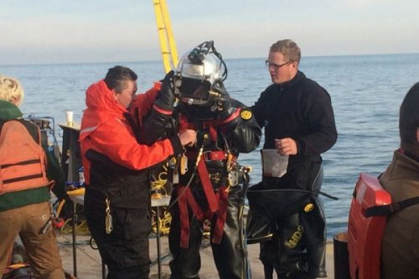 A person in diving gear being inspected by two other people.