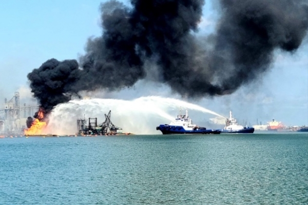 A vessel on fire with smoke billowing from it.