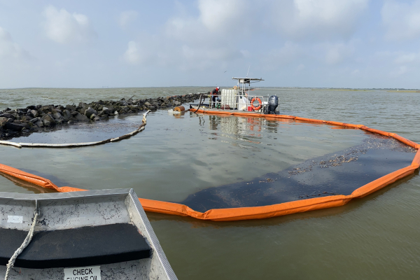 A boat collecting spilled oil in a waterway.