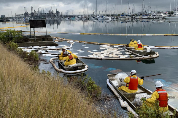 Three boats with responders on board in a marina cleaning up an oil spill.